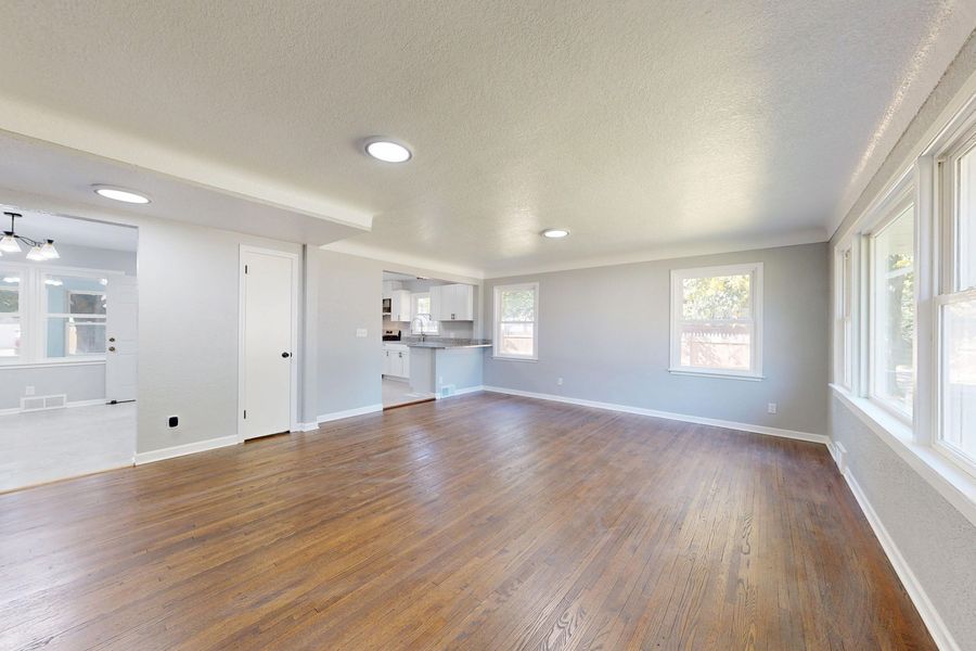 A clean, empty living room with polished timber floors and big windows